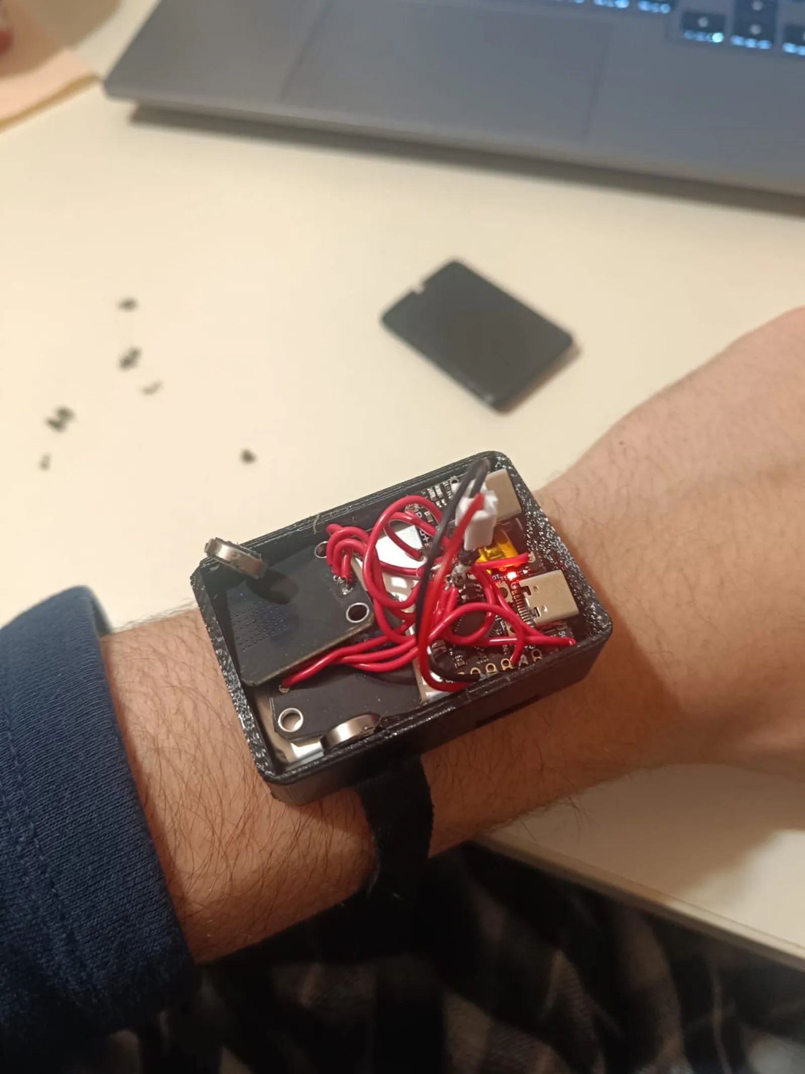 Prototype 1 on the wrist, an open printed case packed with red wire